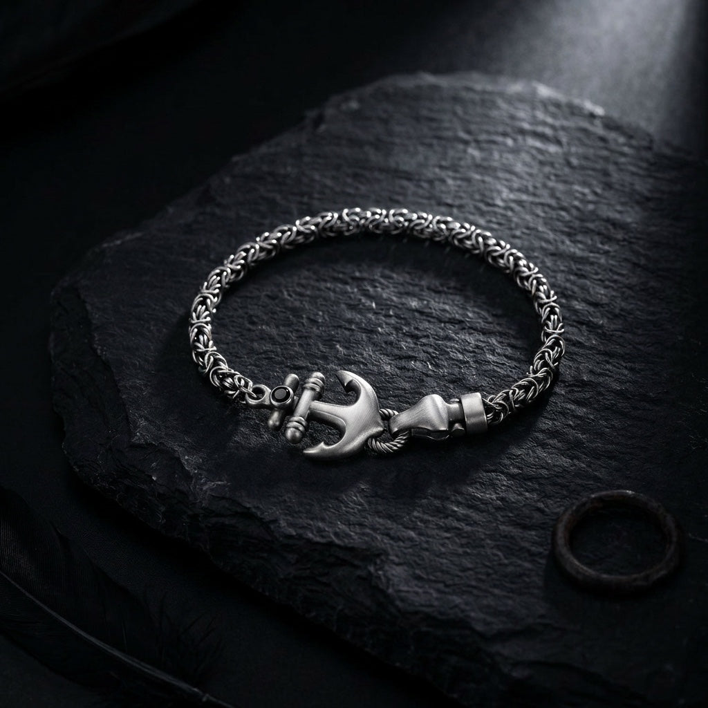 Silver bracelet with an anchor charm on a dark stone surface