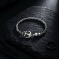 Silver bracelet with an anchor charm on a dark stone surface