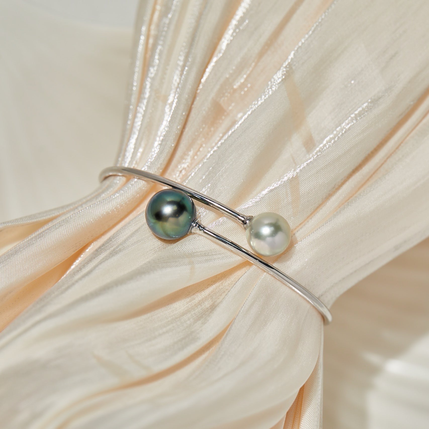 BoxUnboxed 18K white gold bypass bangle with a dark Tahitian pearl and a white Akoya pearl.