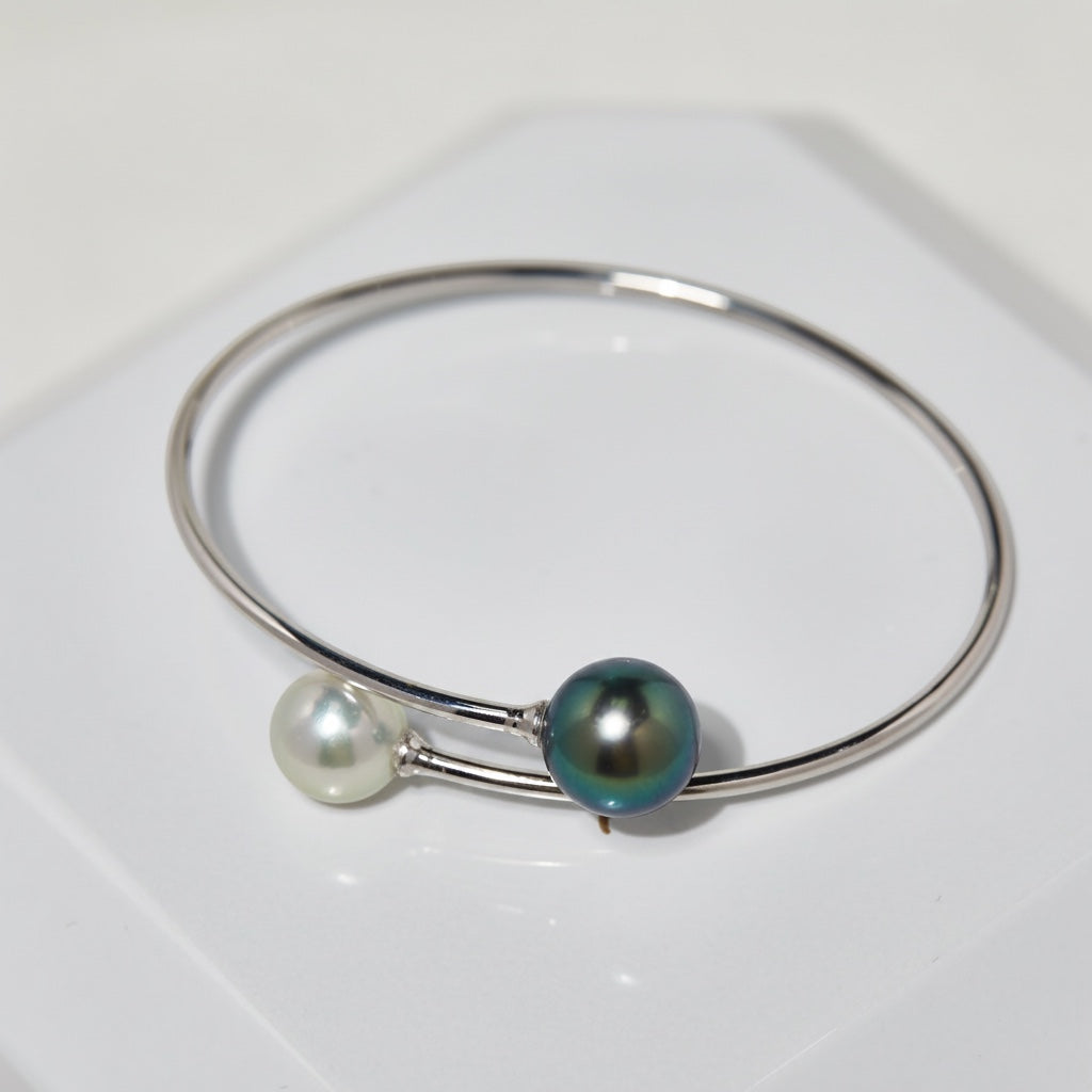 BoxUnboxed 18K white gold bypass bangle with a white Akoya pearl and a dark Tahitian pearl.