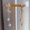 BoxUnboxed gold-plated brass butterfly tassel earrings with freshwater pearls and iridescent shell wings.
