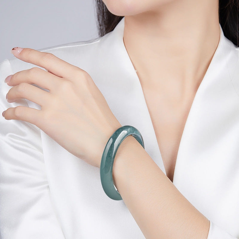 BoxUnboxed Meridian Natural Blue Water Jadeite Bangle, a unisex, smooth, rounded, deep ocean-teal colored jadeite bracelet.